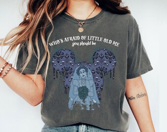 Puede incluir: Camiseta gris oscuro con un gráfico de una novia con un ramo, dentro de un diseño de orejas de Mickey Mouse. El texto "WHO'S AFRAID OF LITTLE OLD ME you should be" está impreso encima del gráfico.