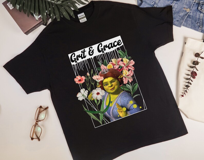 May include: Black t-shirt featuring a graphic print of Shrek, a green ogre, with flowers and the text "Grit & Grace".