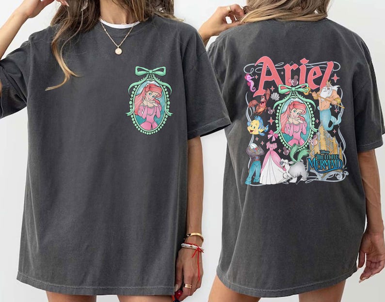 Pu&ograve; includere: Una maglietta grigia oversize con una stampa grafica di Ariel de La Sirenetta. La stampa presenta Ariel con un vestito rosa, una corona e una collana di conchiglie. Il testo "Ariel" &egrave; stampato in grandi lettere sopra l'immagine. Il testo "La Sirenetta" &egrave; stampato sotto l'immagine.