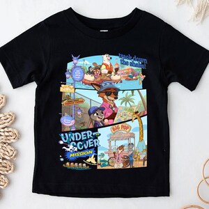 May include: Black short-sleeved t-shirt featuring a colorful graphic design from the animated movie Zootopia. The design includes characters and the text "track down the shade!" and "UNDERCOVER MISSION".