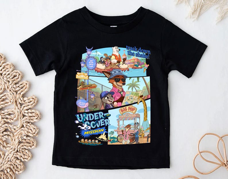 May include: Black short-sleeved t-shirt featuring a colorful graphic design from the animated movie Zootopia. The design includes characters and the text "track down the shade!" and "UNDERCOVER MISSION".