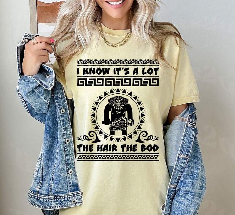 May include: A yellow t-shirt with a black graphic of a cartoon character with the text "I know it's a lot the hair the bod" printed on it.