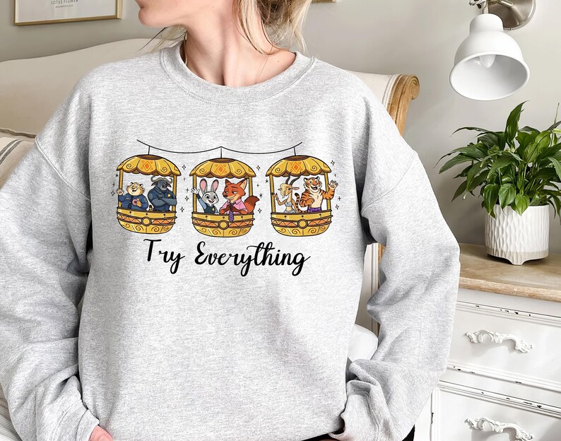 Pode incluir: Camisola cinza claro com um gr&aacute;fico de tr&ecirc;s g&ocirc;ndolas amarelas, cada uma com animais de desenho animado. O texto "Try Everything" est&aacute; impresso em escrita preta abaixo. A camisola &eacute; de gola redonda.