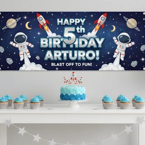 May include: A birthday party scene with a banner that reads "HAPPY 5th BIRTHDAY ARTURO! BLAST OFF TO FUN!" and a cake with rocket ship toppers. Blue and silver balloons and cupcakes decorate the table.