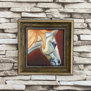 May include: A framed painting of a white horse's head with a reddish-brown mane. The horse is looking to the left, and the background is a dark red.
