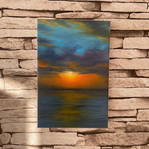 May include: A painting of a sunset over the ocean. The sky is a mix of blue, purple, and orange, with clouds reflecting in the water. The sun is setting in the distance, casting a warm glow over the scene.