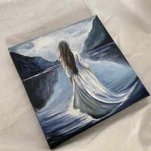 May include: A painting of a woman in a white dress walking on a body of water with mountains in the background.