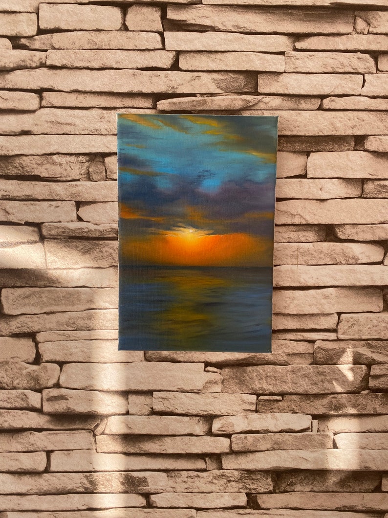 May include: A painting of a sunset over the ocean. The sky is a mix of blue, purple, and orange, with clouds reflecting in the water. The sun is setting in the distance, casting a warm glow over the scene.