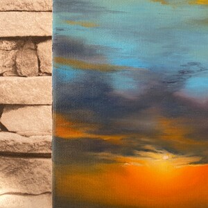 May include: A painting of a sunset over the ocean. The sky is a mix of blue, purple, and orange, with clouds reflecting the light of the setting sun. The water is a dark blue, reflecting the sky above.