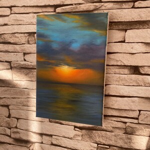 May include: A painting of a sunset over the ocean. The sky is a mix of blue, purple, and orange, with clouds reflecting in the water. The sun is setting in the distance, casting a warm glow over the scene.