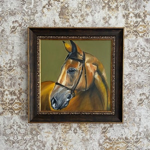 May include: A framed painting of a brown horse with a black bridle. The horse is looking to the left and has a light brown mane and tail. The painting is set against a green background.