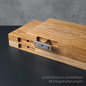 May include: Close-up of two wooden planks with a natural wood grain finish. A metal bracket is attached to the planks, with the text "unsichtbare & verstellbare Montagehalterungen" in the bottom right corner.