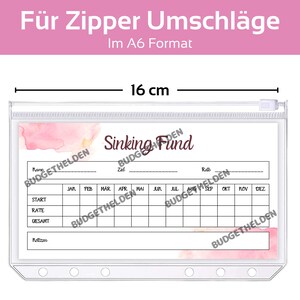 May include: A clear plastic zippered pouch with a white sheet inside. The sheet has a pink watercolour background and the text "Sinking Fund" in brown. The sheet is divided into a grid with columns for each month of the year and rows for "Start", "Rate", and "Gesamt". The pouch measures 8.4 cm by 16 cm.
