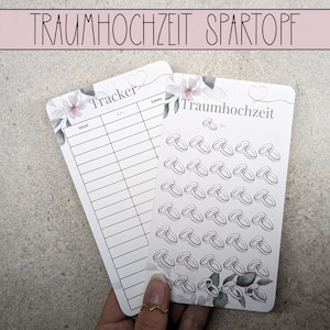 Op de afbeelding: Twee witte kaarten met bloemenontwerpen. Een kaart heeft een checklist met de titel "Tracker" met kolommen voor datum, taak en voltooid. De andere kaart heeft de tekst "Traumhochzeit" en is gevuld met kleine tekeningen van trouwringen.