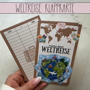 Könnte beinhalten: Eine Reisekarte mit dem deutschen Text "WELTREISE KLAPPKARTE" oben. Die Karte zeigt eine Weltkarte, Reiseaufkleber und die Worte "Meine Spar WELTREISE". Die Karte ist braun mit einem weißen Innenraum für Notizen.