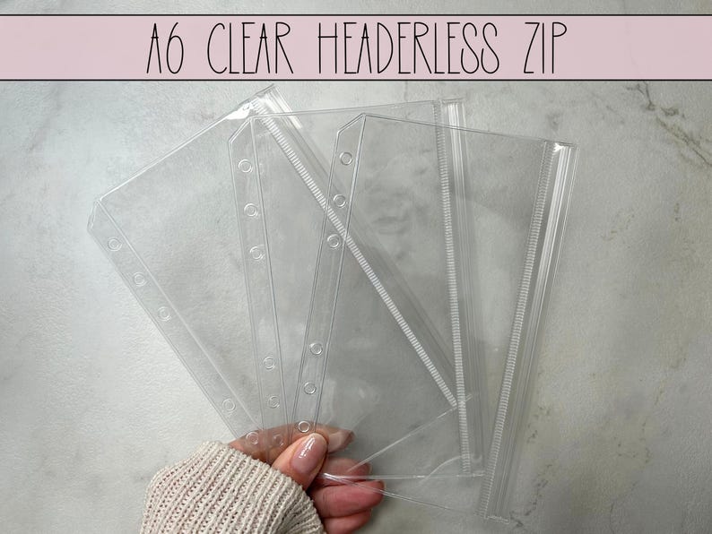 May include: Four clear plastic A6 zippered pouches with holes for a binder. The pouches are stacked on top of each other.