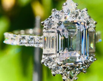 May include: A silver ring with a large, clear emerald-cut center stone surrounded by smaller, round stones. The ring has a delicate band with small stones set along the edge.