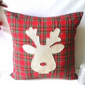 Puede incluir: Cojín de cuadros rojos y verdes con una aplicación de reno de fieltro beige.