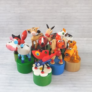 May include: A set of colorful wooden puppet toys, including a cow, a dog, a butterfly, a unicorn, and a ladybug. The puppets are on wooden bases and are ready to be played with.