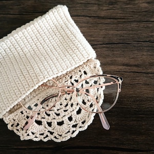May include: A crocheted eyeglass case with a delicate lace design and a pair of rose gold eyeglasses.