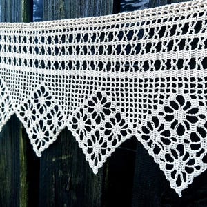 Könnte beinhalten: Weißer Häkelspitzenbesatz mit einem gewellten Rand und einem sich wiederholenden Blumenmuster.