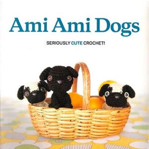 Op de afbeelding: Ami Ami Dogs boekomslag met drie gehaakte hondenfiguren in een rieten mand met sinaasappels. De titel van het boek is blauw, met de ondertitel "Seriously Cute Crochet!" eronder.