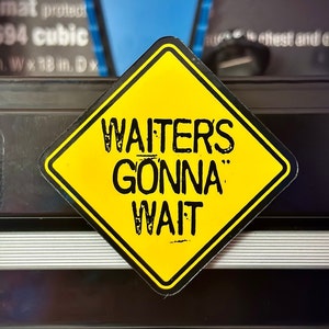 May include: Yellow diamond-shaped warning sign with black text that reads "Waiters Gonna Wait".