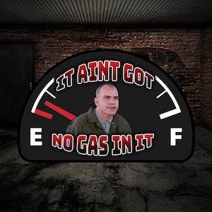 May include: A black and white gas gauge with a red needle pointing to empty. The gauge reads "It ain't got no gas in it".