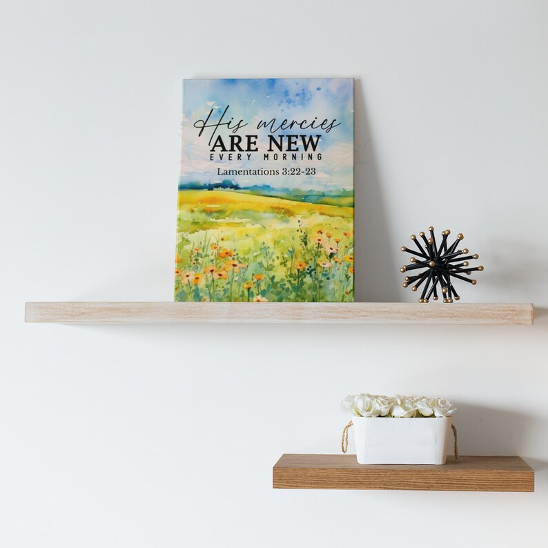 May include: A watercolor painting of a field of flowers with a blue sky in the background. The text "His mercies are new every morning" and "Lamentations 3:22-23" are printed on the painting.