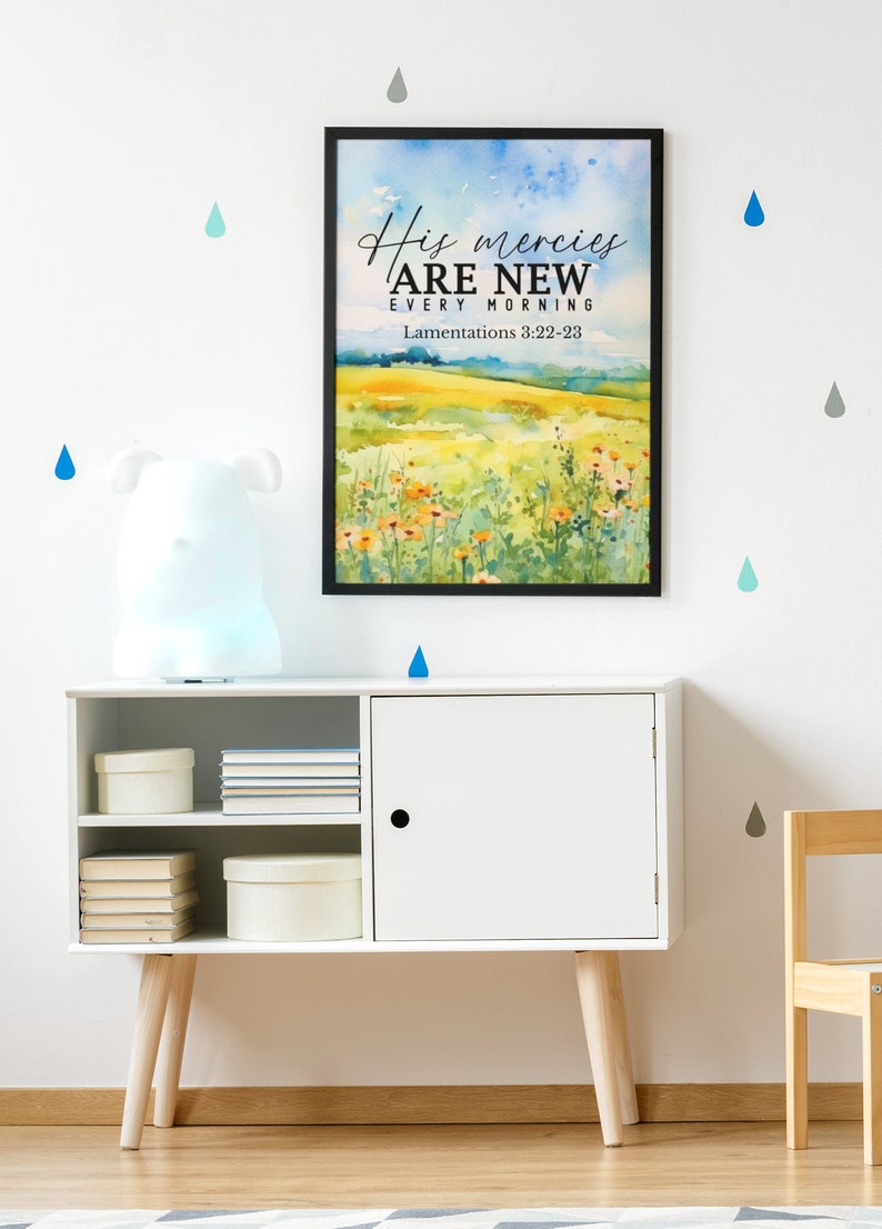 May include: A framed watercolor print with a quote about God's mercies being new every morning. The quote is from Lamentations 3:22-23. The print is hanging on a white wall with blue and gray raindrops.