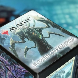 May include: Black card storage box with "MAGIC THE GATHERING" logo and "SLIVER OVERLORD" text. The box features fantasy art of a creature on the lid and side panels, with a card visible.