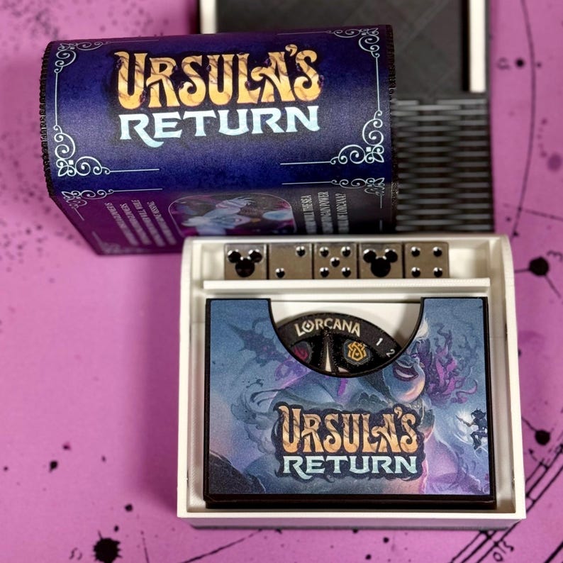 May include: A close-up of a board game called "Ursula's Return" by Lorcana. The game box is open, revealing the game board and dice. The game board features a purple and blue design with an illustration of Ursula from Disney's The Little Mermaid.