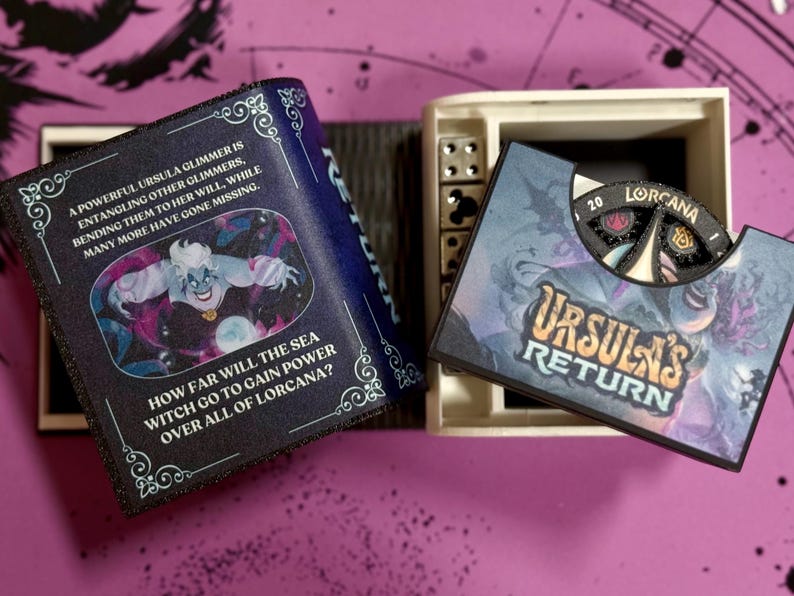 May include: A black and blue book with a picture of Ursula from The Little Mermaid. The book has the text "A powerful Ursula glimmer is entangling other glimmers, bending them to her will, while many more have gone missing." and "How far will the sea witch go to gain power over all of Lorcana?" The book is open to reveal a white box with a black and blue card that says "Ursula's Return" and has a spinning wheel with the text "20 Lorcana".