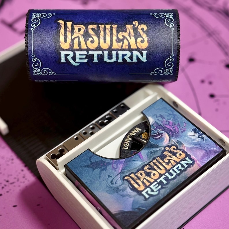 May include: A white box with a blue and gold can on top. The can has the text "Ursula's Return" on it. The box has a blue and purple image of Ursula with the text "Ursula's Return" on it.