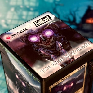 May include: A Magic: The Gathering card box featuring the Fallout theme. The box art displays a close-up of a creature with glowing purple eyes, labeled "The Wise Mothman." The "Fallout" logo is visible.