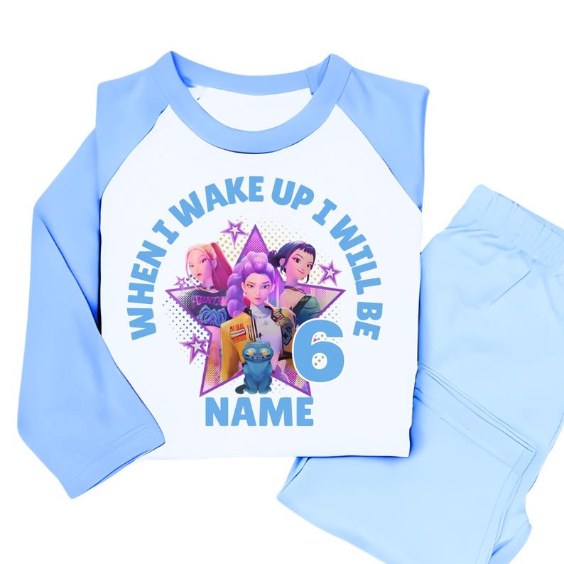 May include: A light blue and white pajama set with a graphic featuring three animated figures and the text "WHEN I WAKE UP I WILL BE 6 NAME". The set includes a long-sleeved top and matching pants.