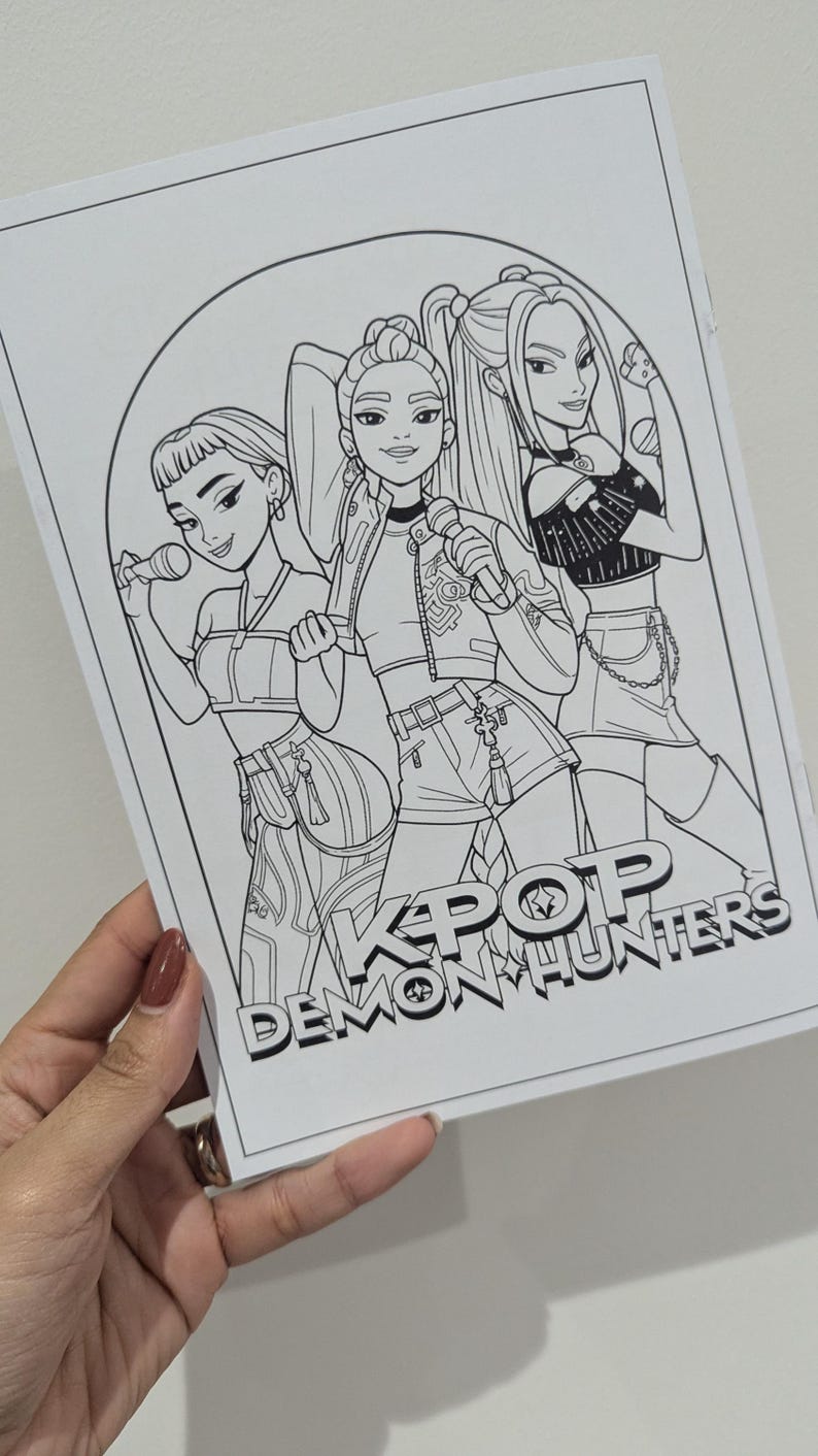 Op de afbeelding: Zwart-wit illustratie van drie vrouwen met microfoons, met de tekst "KPOP DEMON HUNTERS". De vrouwen dragen modieuze outfits, waaronder crop tops en shorts.