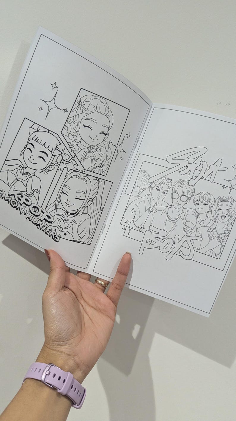 Op de afbeelding: Een open kleurboek met zwart-wit illustraties van stripfiguren. Het boek toont tekeningen met de tekst "KPOP MON HUNTERS" en "Six Boys POPS". Een hand, met een lichtpaars horloge, houdt de pagina's open.