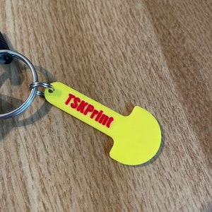 Könnte beinhalten: Gelber Schlüsselanhänger aus Kunststoff mit abgerundetem Ende und einer roten Aufschrift "TSKPrint".
