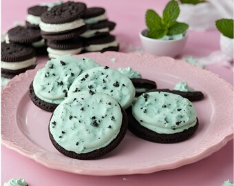 Puede incluir: Un plato de galletas caseras de chocolate con menta con glaseado verde claro y chispas de chocolate. Las galletas están en un plato rosa con un borde decorativo.