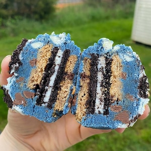 Op de afbeelding: Een blauwe koekdeegtraktatie met lagen chocolade, witte chocolade en koekkruimels. Het koekdeeg is doormidden gesneden om de lagen aan de binnenkant te laten zien.