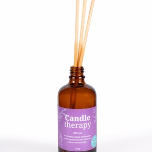 May include: A brown glass diffuser bottle with a purple label that reads "Candle therapy Diffuser An dreamy blend of lavender, sweet marjoram and Patchouli pure essential oils 100g". The bottle has wooden sticks inserted into the top.