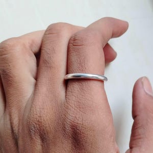 May include: A simple silver band ring worn on a finger.