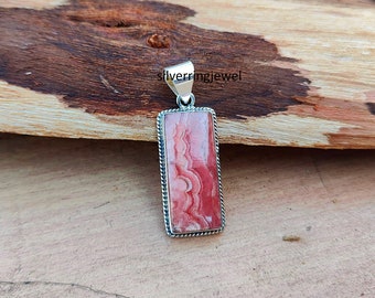 May include: A silver pendant with a rectangular pink and white agate stone. The stone has a swirling pattern and is set in a silver frame with a rope-like border.
