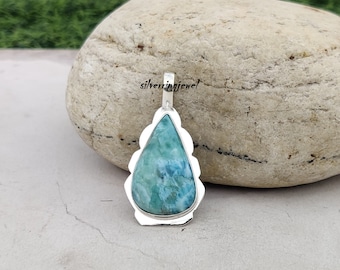May include: A teardrop-shaped pendant with a blue and green gemstone set in a silver bezel. The pendant is on a white background.