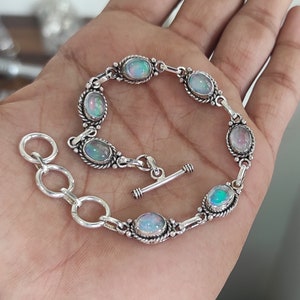 May include: A silver bracelet with a toggle clasp and oval-shaped opal stones.