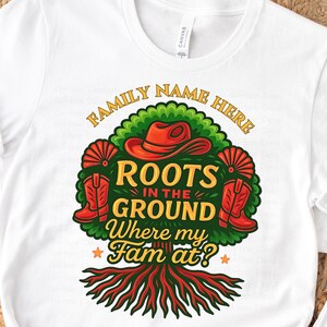 May include: White t-shirt with a colorful graphic design. The design features a tree with roots, a cowboy hat, boots, and the text "Roots in the Ground Where my Fam at?" in a stylized font. The words "Family Name Here" are arched above the tree.