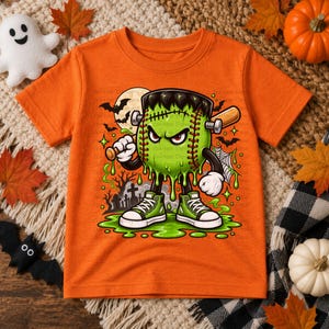 May include: An orange short-sleeve t-shirt featuring a graphic of a green baseball character with Frankenstein-like features, including bolts on the sides of its head, holding a wooden baseball bat, standing in green slime with sneakers.