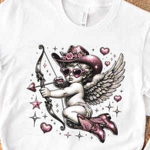 May include: A pink and white illustration of a cupid with wings, wearing a pink cowboy hat and sunglasses, holding a bow and arrow. The cupid is surrounded by pink hearts and stars.