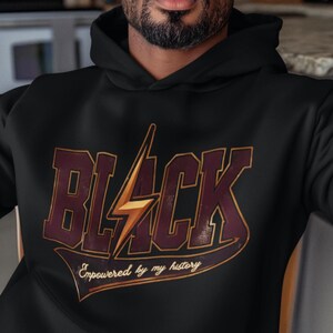 May include: Black hoodie with a vintage-style graphic that says "BLACK" with a lightning bolt and the text "Empowered by my history".